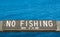 Wooden `No Fishing` sign at the Pacific ocean