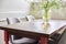 Wooden oak table in living room interior, on table vase with flowers, chairs