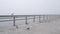 Wooden Ocean Beach pier in fog, misty calm boardwalk in haze, California coast.