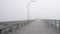 Wooden Ocean Beach pier in fog, misty calm boardwalk in haze, California coast.