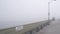 Wooden Ocean Beach pier in fog, misty calm boardwalk in haze, California coast.