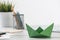 Wooden office desk with green origami boat.