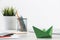 Wooden office desk with green origami boat.