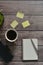 Wooden office desk table with a notebook, a handle, phone, a cup of coffee and a flower pot.