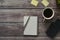 Wooden office desk table with a notebook, a handle, phone, a cup of coffee and a flower pot.