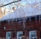 Wooden old house with icicles on the roof