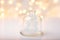 Wooden ornament Christmas tree in crystal jar golden garland sparkling bokeh lights on white background. Festive New Years card