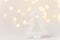 Wooden ornament Christmas tree in forest golden bokeh garland lights white background. New Years holiday magic atmosphere