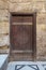 Wooden ornate door with geometrical engraved patterns on external old decorated bricks stone wall