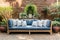 Wooden outdoor couch with blue and white textile cushions. Green potted plants. Georgian style residential house