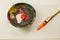 Wooden paint mixing bowl white and orange wet paint smeared small paint brush