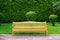Wooden park bench with sidewalk and green lawn.