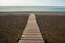 Wooden path on the sandy beach. Beach boardwalk with sand texture background