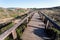 Wooden path from sunny beach to village through rural landscape, Portugal. Green hills in peaceful natural area