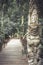 Wooden pathway leading to tropical forest with terrible statues of Asian Buddhism demon in vintage style