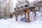 Wooden pavilion and blue picnic table on a snowy and hilly terrain in winter