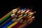 Wooden pencils in all colors seen from the sheet of pencils. Colored pencils stacked with a black background. Colors. Back to
