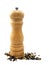 A wooden peppermill with peppercorns