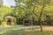 Wooden pergola and swing in garden with lamp and trees.