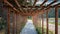 Wooden pergola (treillage) above cobblestone sidewalk leading along lake shoe and forest. One-point perspective
