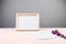 Wooden photo frame with white blank card against a gray wall. Mock up poster frame. Stylish template