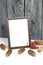 Wooden photo frame with a white field for an inscription or a picture. Nearby are spruce cones and a bunch of dried mountain ash