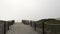 Wooden picket fence, sandy misty beach, California USA. Pacific ocean coast, fog haze on sea shore.