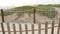 Wooden picket fence, sandy misty beach, California USA. Pacific ocean coast, fog haze on sea shore.