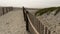 Wooden picket fence, sandy misty beach, California USA. Pacific ocean coast, fog haze on sea shore.
