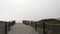 Wooden picket fence, sandy misty beach, California USA. Pacific ocean coast, fog haze on sea shore.