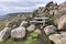 Wooden picnic table sits on the rocks overlooking the mountains in the background with rock cliffs. Haifoss waterfall area in