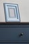 Wooden picture frame on blue chest of drawers