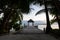 Wooden pier extending into the ocean with lush palm trees around  and thatched bungalow at the end, Maldives