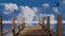 Wooden pier fly-through over blue ocean with a fast white clouds timelapse