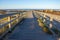 Wooden pier with grass on Atlantic ocean coast, Portugal. Wooden boardwalk to sea on rocks shore. Empty walkway in dunes at dawn.