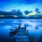 Wooden pier or jetty and a boat on a lake sunset. Versilia Tuscany, Italy