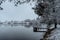 Wooden pier on lake with fresh snow.Winter pond with small jetty on misty morning.Foggy cloudy landscape reflected in water. White