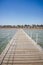 Wooden pier leading to the shore on a sunny day/beautiful wooden pier at the sea leading to the shore with blue sky