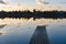 Wooden pier with leaves on the quiet lake in autumn