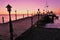 Wooden pier lighted by pink sunrise glow
