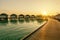 Wooden pier and line of tropical villas at sunrise time, Maldives