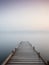 A wooden pier at misty dawn in a still sea