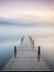A wooden pier at misty dawn in a still sea
