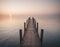 A wooden pier at misty dawn in a still sea