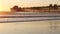 Wooden pier on piles, silhouette at sunset, California USA, Oceanside. Sunny sea waves at sundown.