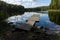 Wooden pier with the reflection of landscape and clouds in a lake in summer.