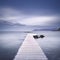 Wooden pier, rocks and sea on misty sunset.