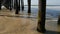 Wooden piles under pier in California USA. Pilings, pylons or pillars below bridge. Ocean waves tide