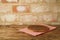 Wooden pizza tray on table with tablecloth over brick wall background