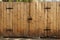 Wooden plank fence with closed gate door with black iron details and lock bolt